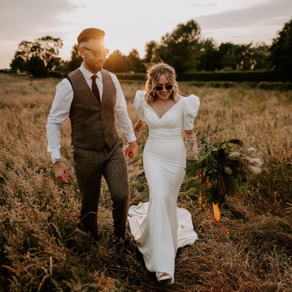 Bride wearing black wedding sunglasses with the groom as they pose during golden hour for their couple portraits 