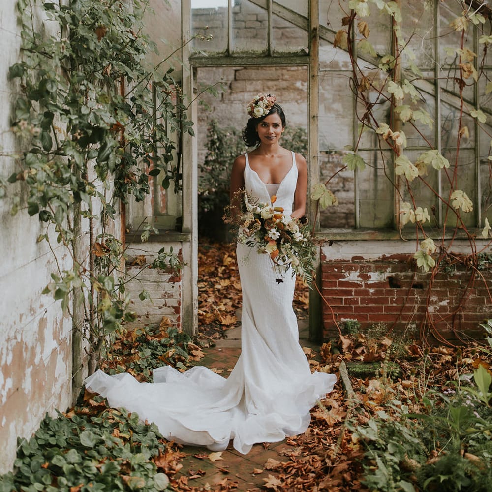 Bride in wedding dress with straps and sequins holding an autumn wedding bouquet 