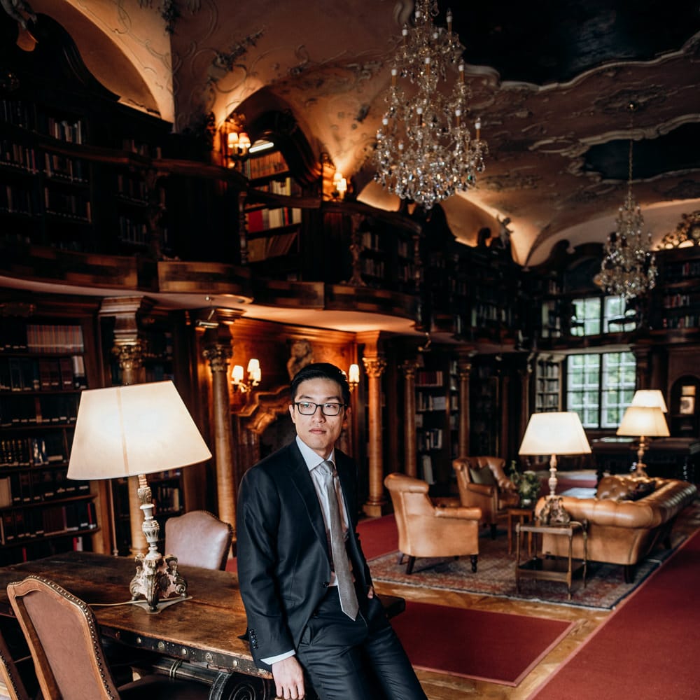 Groom in dark suit standing in the library 