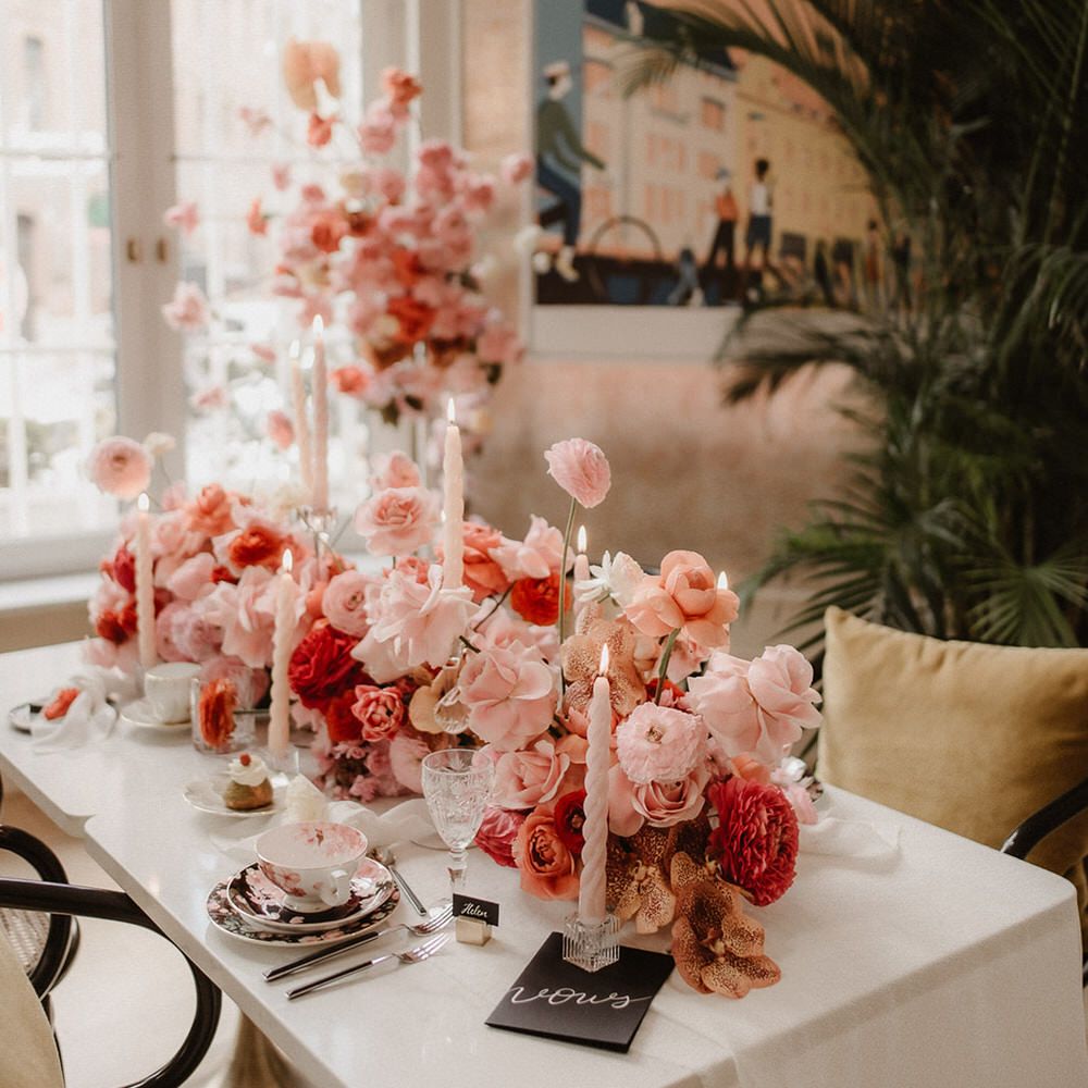 Luxe wedding tablescape with peach wedding flowers including pink, peach and burgundy ranunculi, garden roses and orchids