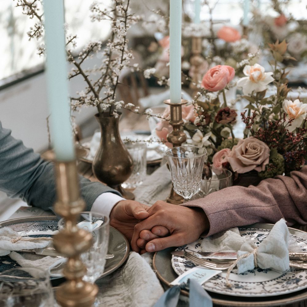 Rustic tablescape with floral decor as grooms reach across to hold hands with one another