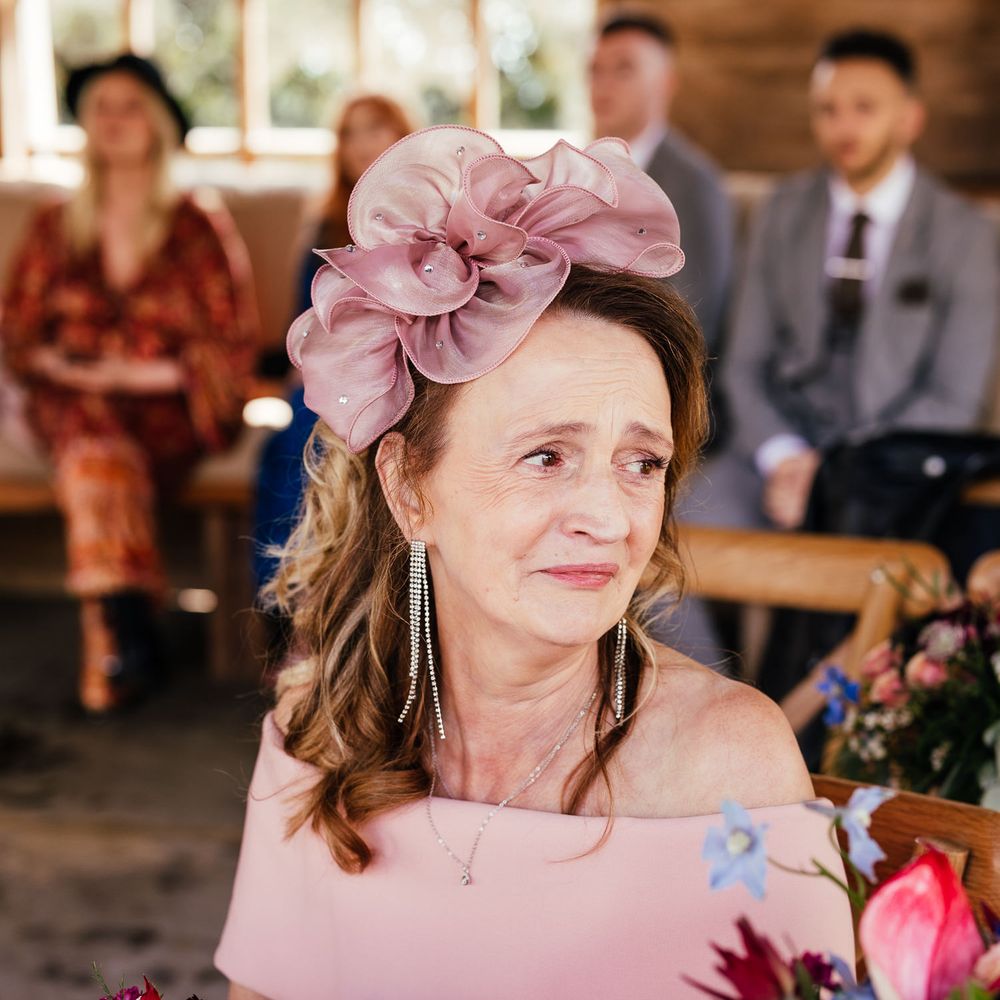 Mother of the bride wears pink dress and fascinator 