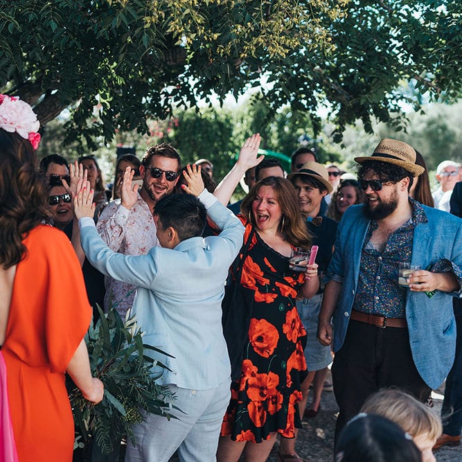 Brides celebrate with guests on their wedding day as they high five 