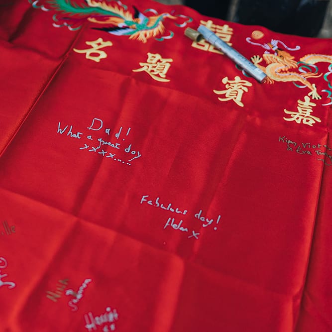 Wedding guests sign red fabric with embroidery to the top