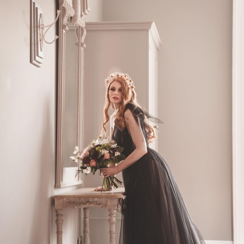 Bride with long wavy auburn hair wearing a headdress and black tulle wedding dress