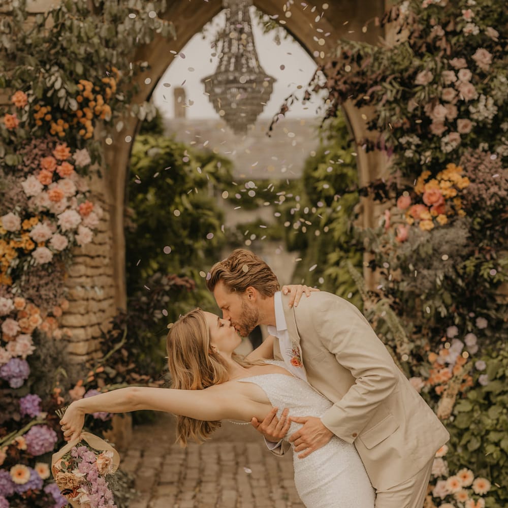 Groom in a beige suit leaning his bride over for a kiss in a sparkly Made With Love dress at Euridge Manor 