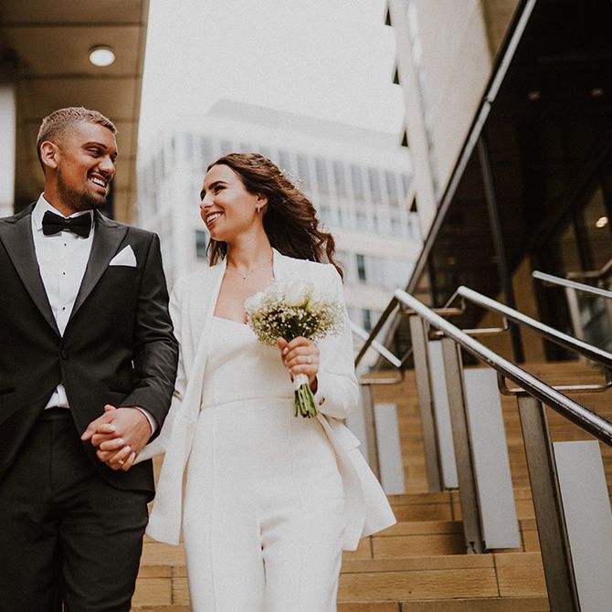 Bride and groom portrait with groom in a black tuxedo and bride in a white suit both from Reiss 