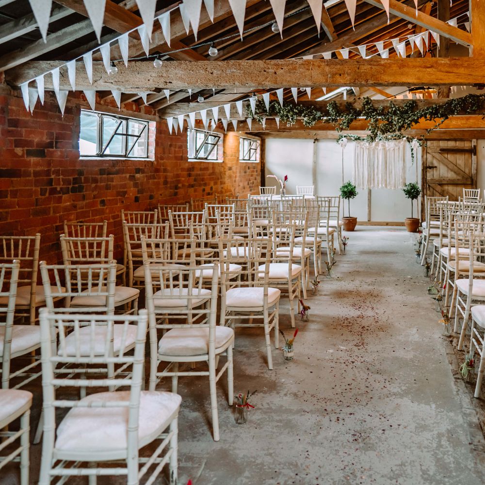 Wedding ceremony venue in barn complete with white chairs and rustic vibe