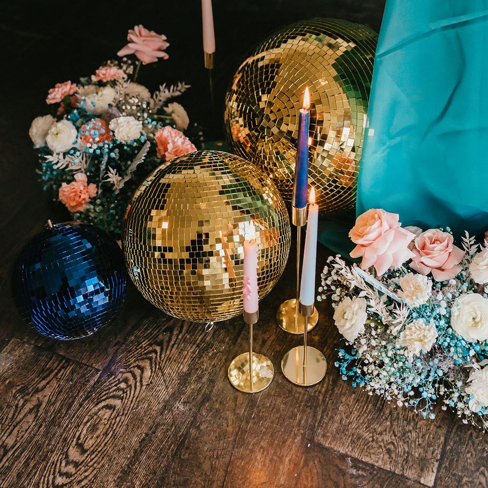 Gold glitter balls, pink and white flowers, candles and a teal table cloth wedding decor 