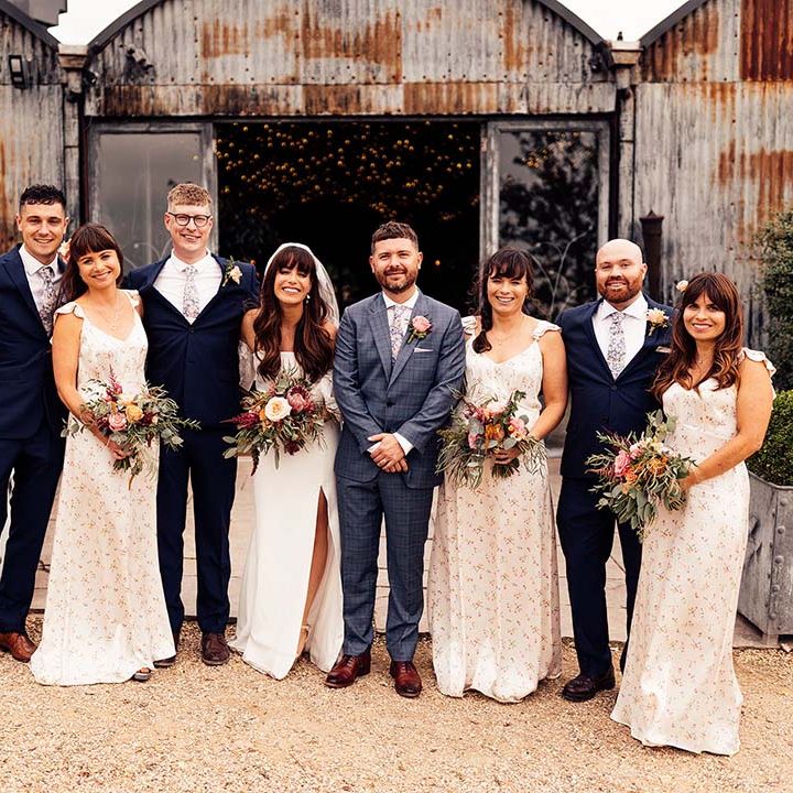 Bride & groom stand with their family outdoors after wedding ceremony