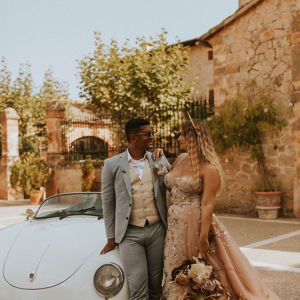 Bride & groom stand beside car on their wedding day