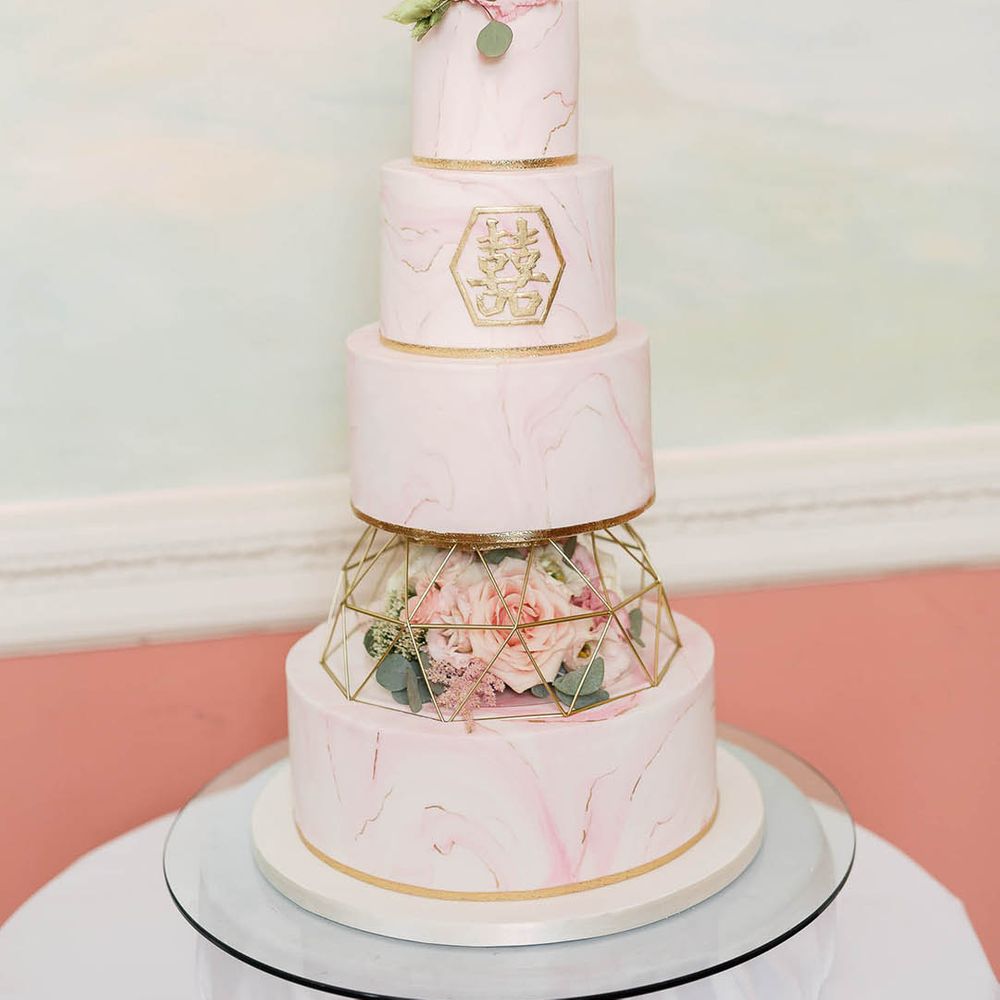 4-tier marble wedding cake complete with blush pink frosting and gold detailing 