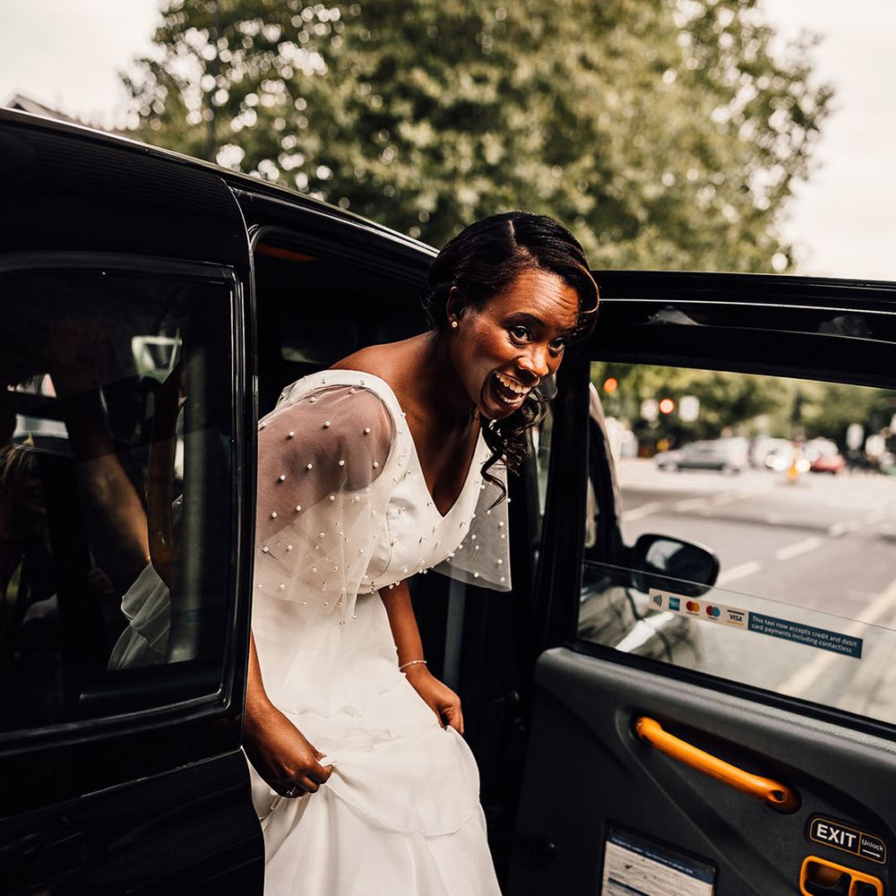 Bride getting out of a London Black Cab in a layered skirt and pearl top 