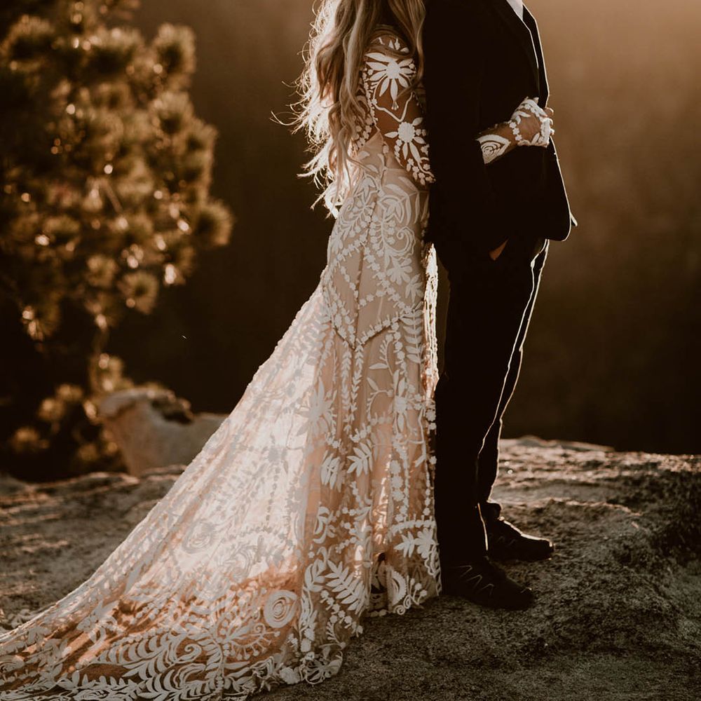 Bride & groom embrace on mountain as the sun sets 