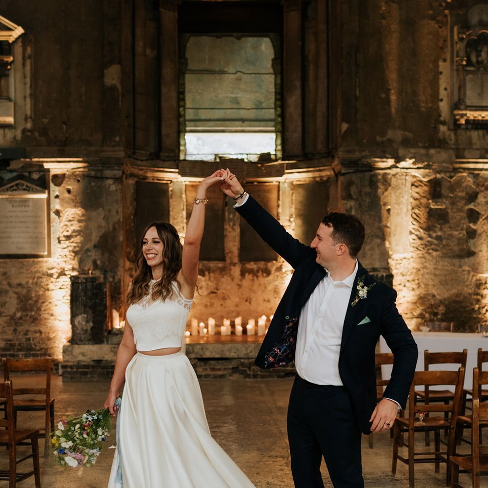 Bride wearing pleated high low wedding skirt showing off electric blue wedding shoes with groom in navy blue suit