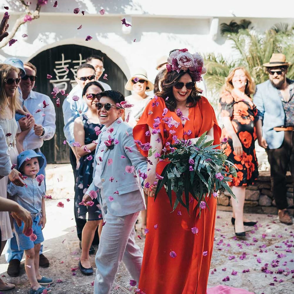 Couple walk through pink confetti on their wedding day after marrying