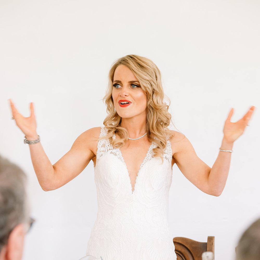 Bride in v neck lace wedding dress with curled blonde hair and red lipstick 