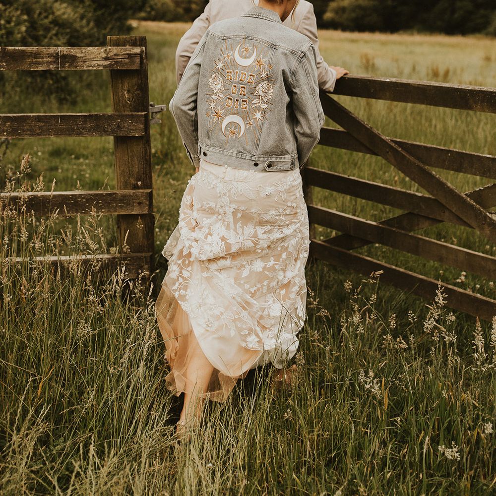 Bride in a light blue denim jacket with a cool design on the back for rustic wedding 