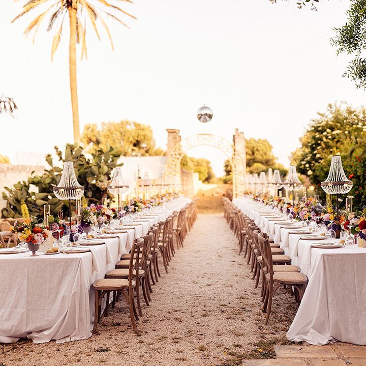 Puglia destination wedding with chandelier installations over the outdoor banquet tables for the reception 