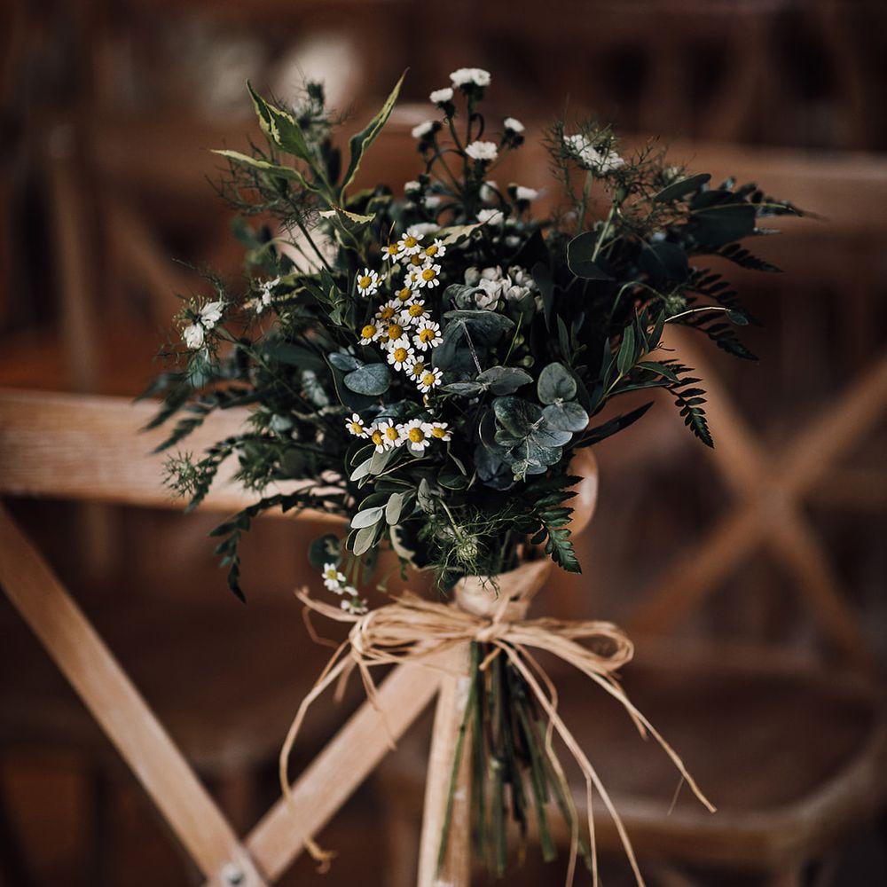 White flowers tied with string onto the chairs for aisle decoration 