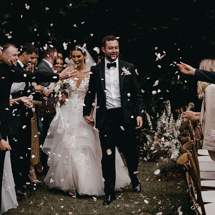 Bride in a Wtoo by Watters wedding dress walking with the groom in black tie having their confetti moment 