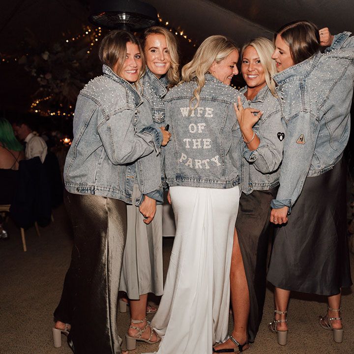 Bride and bridesmaids in blue denim jackets decorated with pearls and a personalised cover up for the bride 