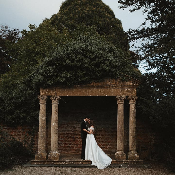 A classic black tie wedding at Brympton House with the bride and groom posing together 