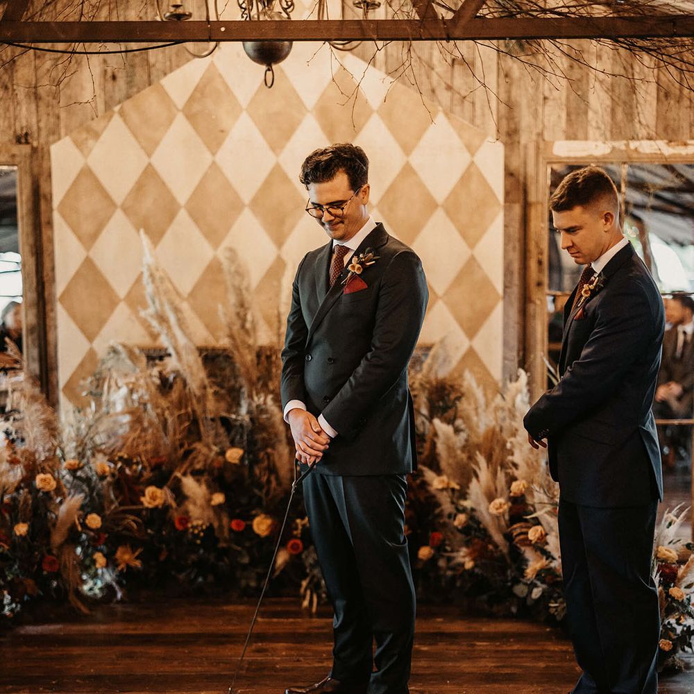 Groom wears bespoke suit and holds sausage dog at The Dreys wedding venue