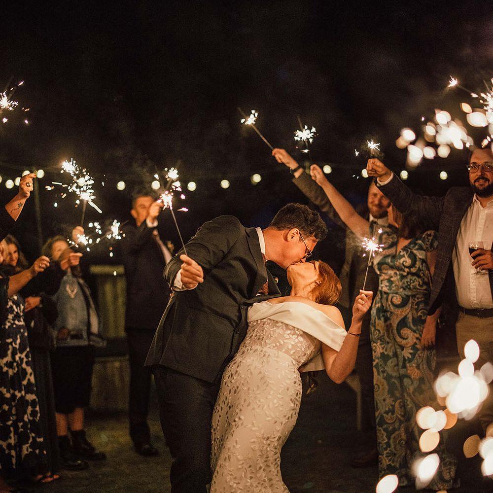 Groom kisses his bride during sparkler exit 