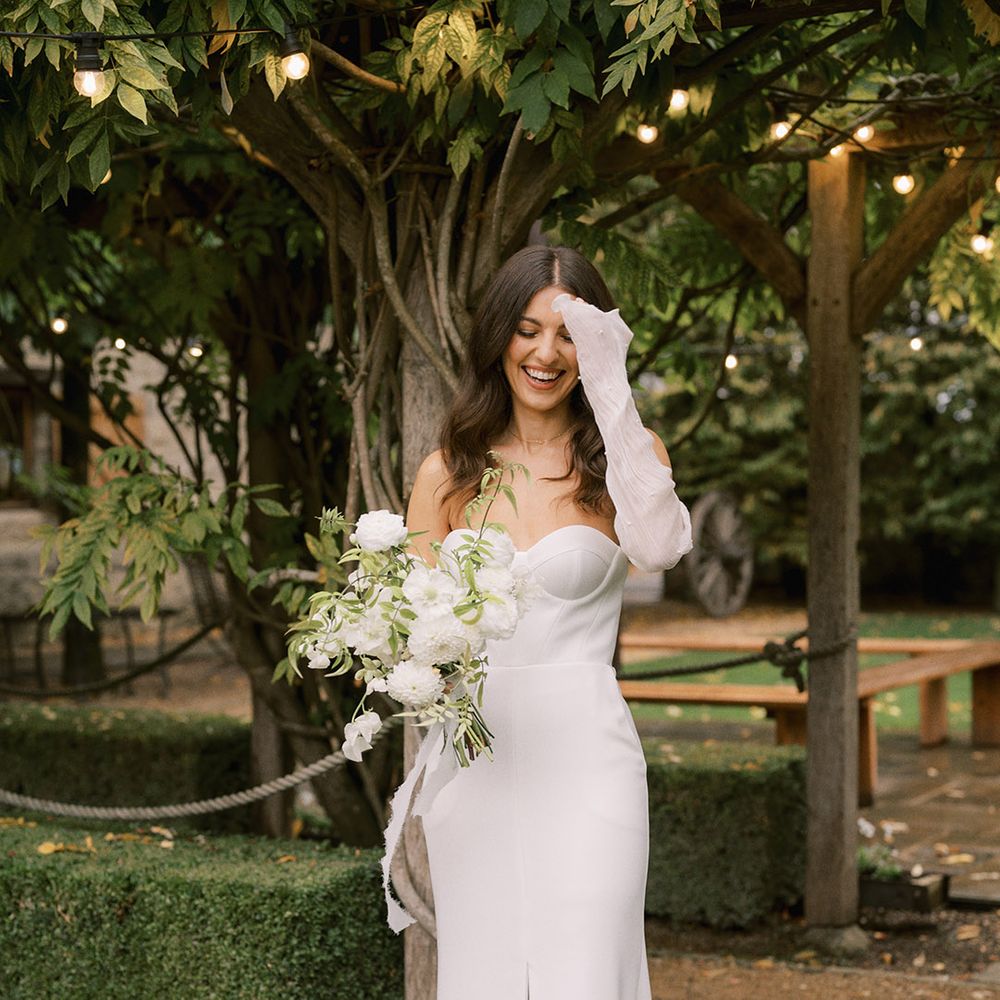 Bride in Bon Bride wedding dress with detachable pearl sleeves and Jimmy Choo pearl shoes with all white flower bouquet 