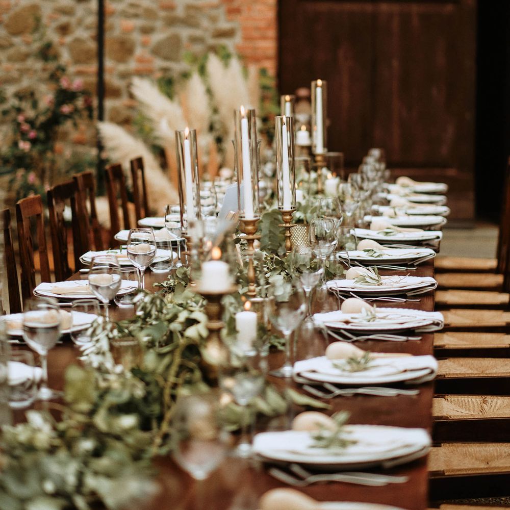 Wedding tablescape featuring eucalyptus decor with tapered candles, wine glasses and maraca favours