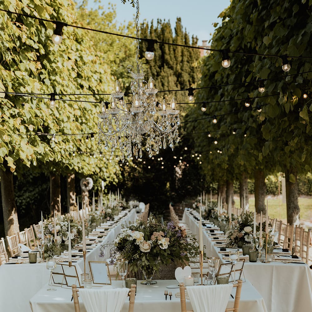 Sweetheart top table for the bride and groom at their outdoor wedding breakfast with white drapery chair back decor 