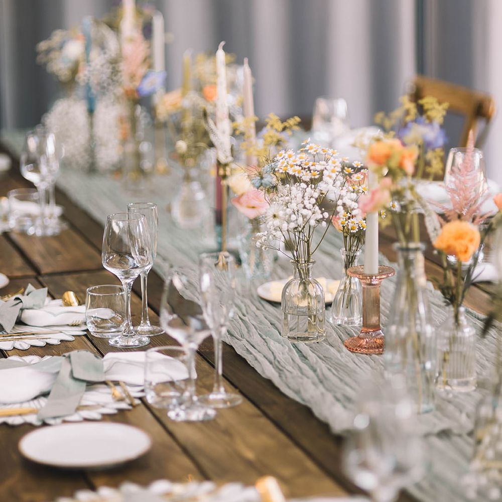 Pastel wedding theme tablescape with colourful bud vases, flowers, candles, and more at industrial style venue 