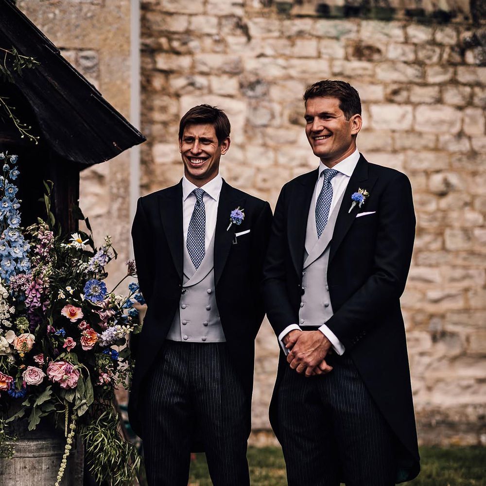 Groom and groomsman in morning suits with blue wedding tie and blue flower buttonhole 