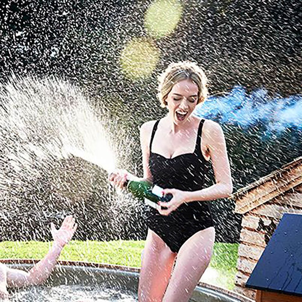 Image of a woman spraying a bottle of bubbles in a hot tub