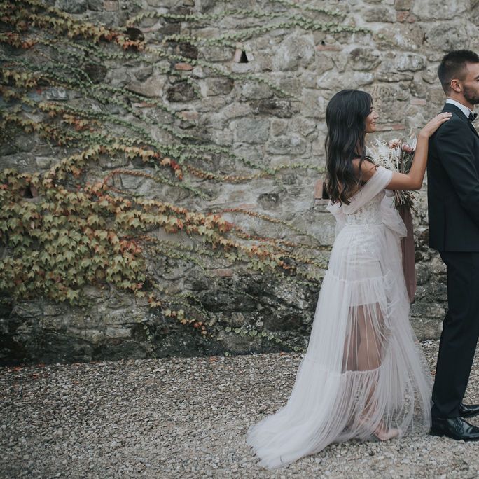 Bride in blush wedding dress tapping her groom on the shoulder 