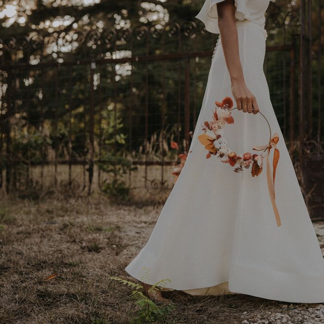 Bride in an a line wedding dress holding an autumn flower hoop 