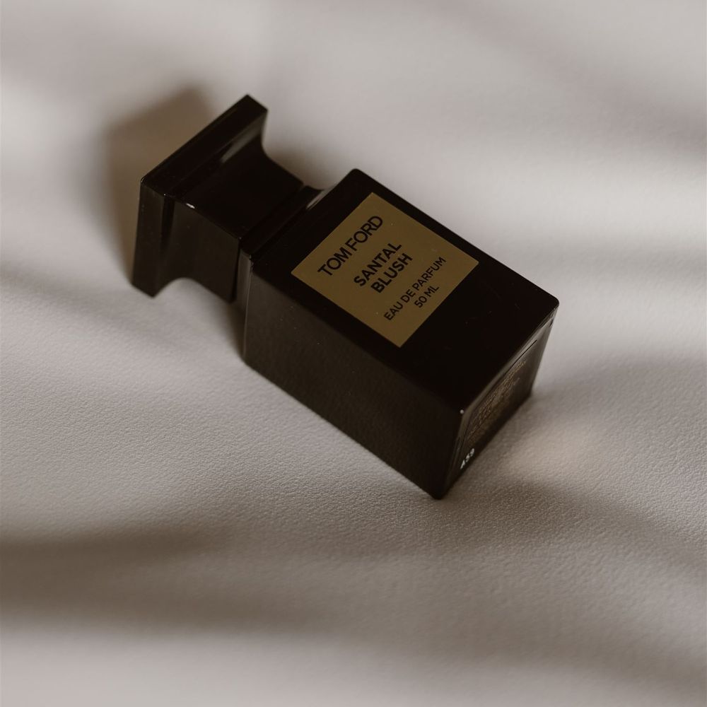 Black bottle of Tom Ford Santal Blush Eau De Parfum on white bedspread