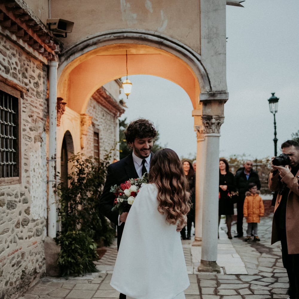 The bride and groom outside their church wedding ceremony, the bride is wearing a long white bridal cape