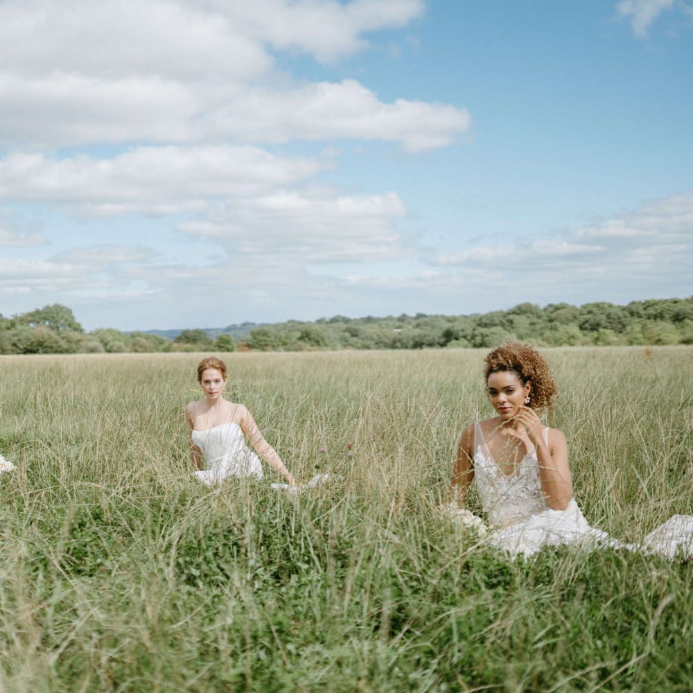Three boho style brides sitting in the fields at Berwick Lodge