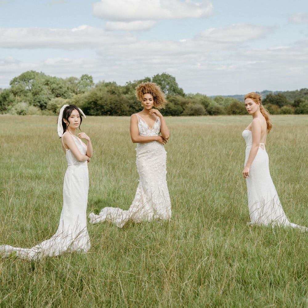 Three brides in the fields at Berwick Lodge wearing boho inspired wedding dresses from Made With Love and Emmy Mae Bridal