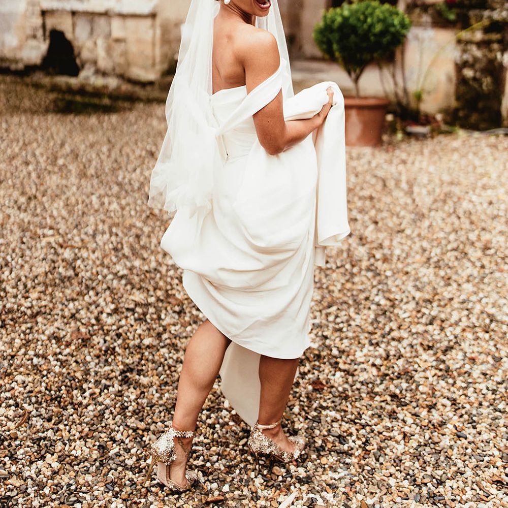 Bride lifts her gown as she walks outdoors for French wedding