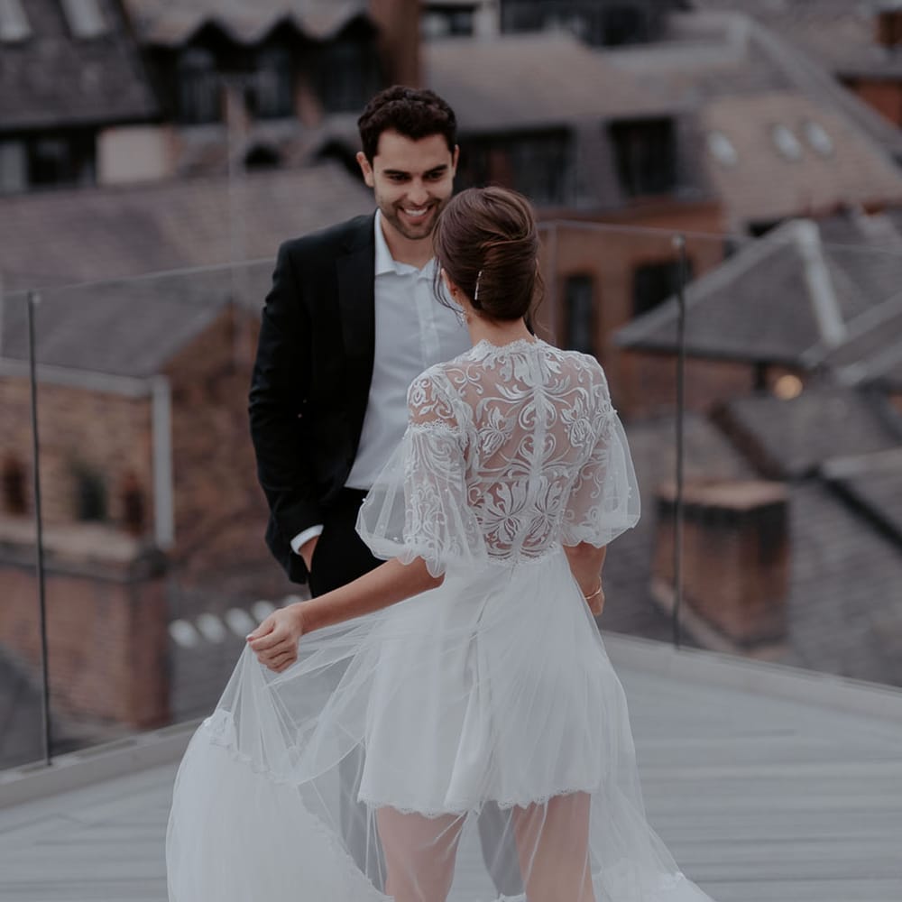 Bride with a chic chignon wedding hairstyle wearing a layered tulle wedding dress with embroidered lace bodice and short puff sleeves