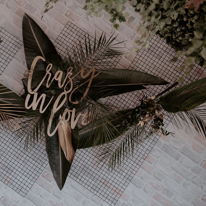 Crazy In Love lasercut sign on a green foliage back drop for urban jungle wedding at Manchester Hall 