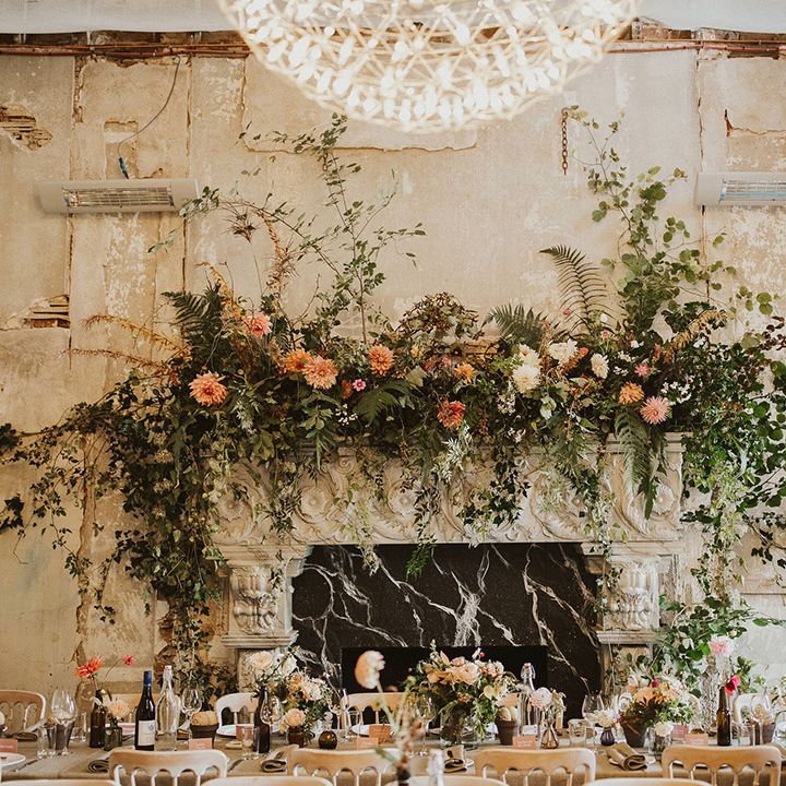 Rustic reception venue complete with large floral installation across fireplace 