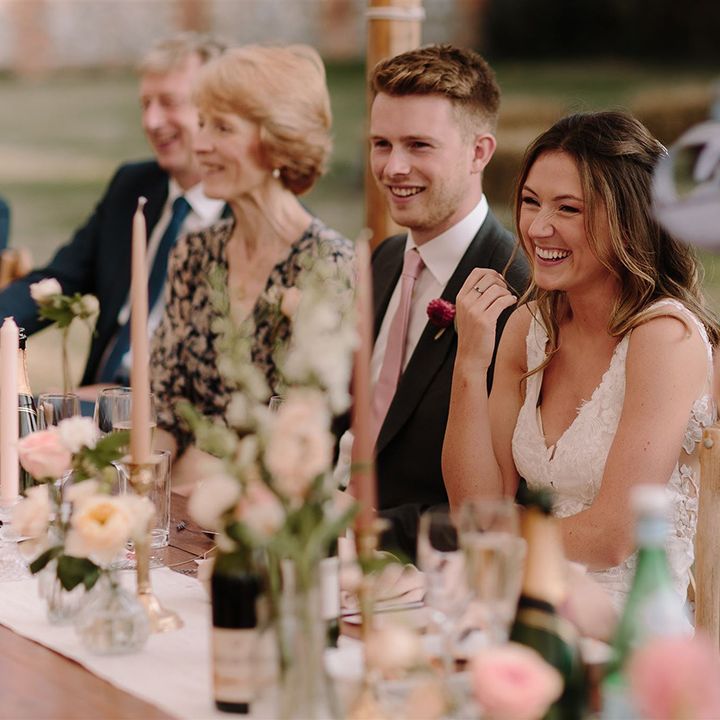 Bride and groom enjoy wedding speeches in marquee