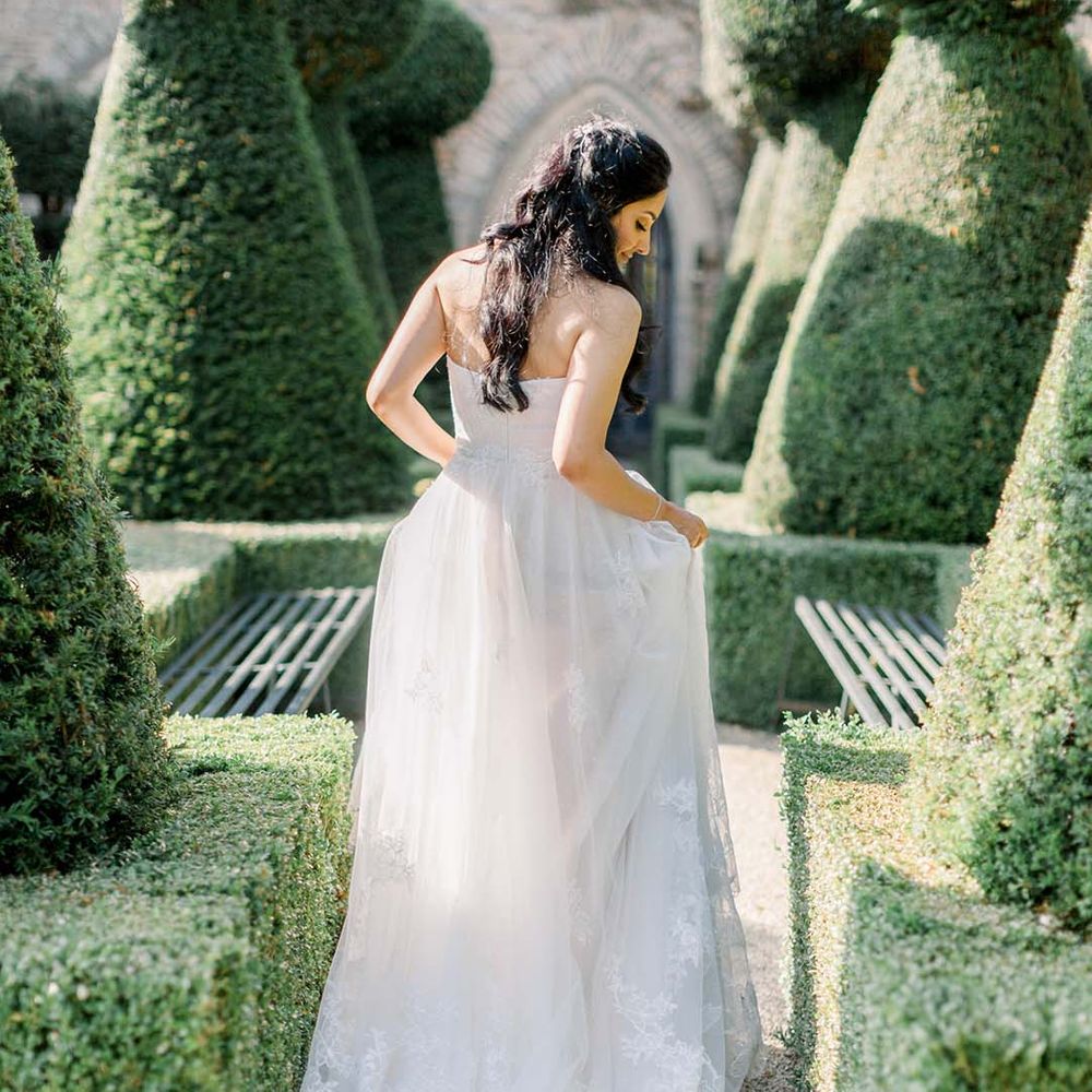Bride walks through manicured gardens of Euridge Manor on her wedding day