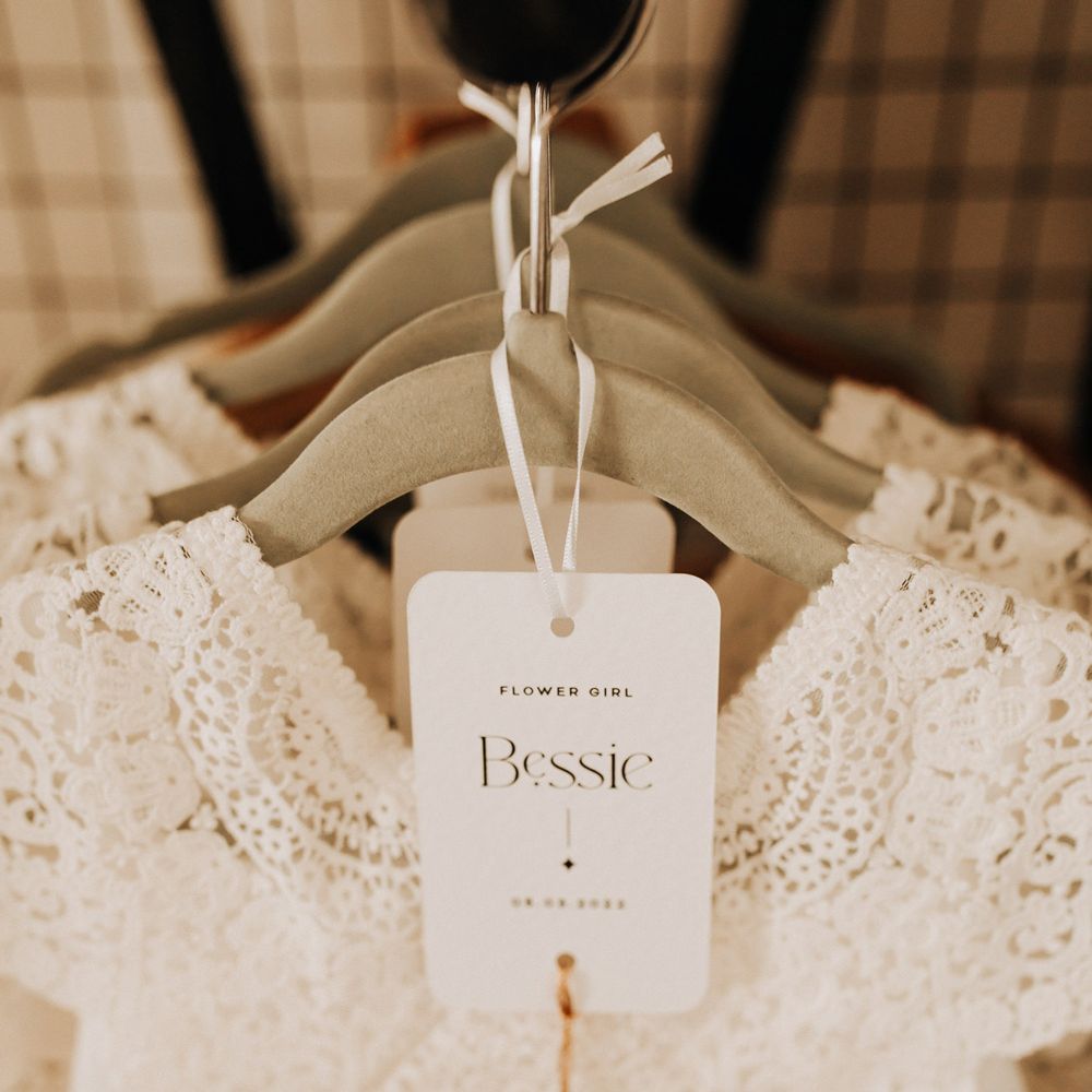 White crochet flower girl dress with monochrome name tag and tassel