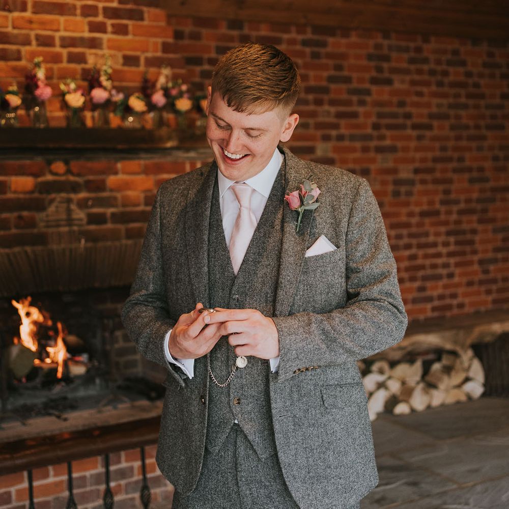 Groom in grey tweed suit with pink tie and pink rose boutonnière and silver pocket watch