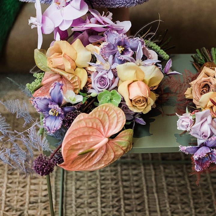 Orange, yellow and purple flower wedding bouquets next to pearl handbag accessory